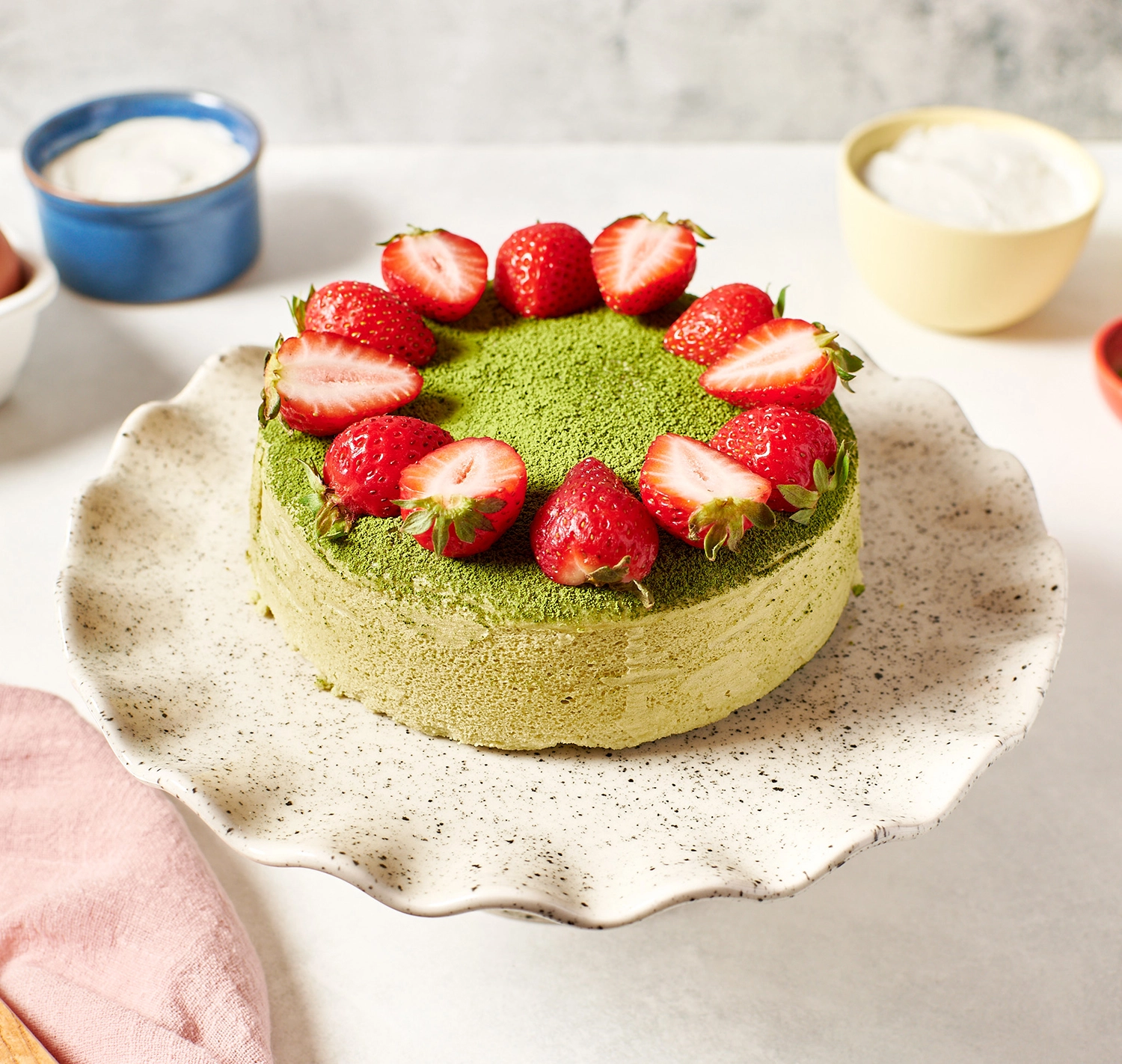 Fluffy Japanese matcha cheesecake garnished with fresh strawberries.