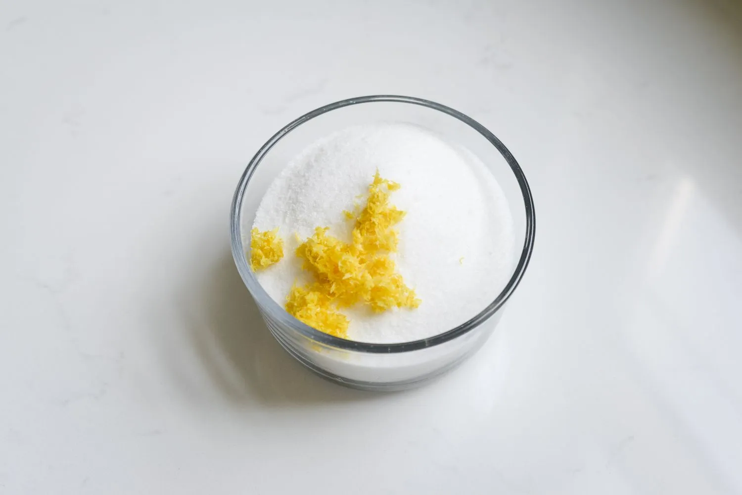 A small bowl filled with sugar and lemon zest.