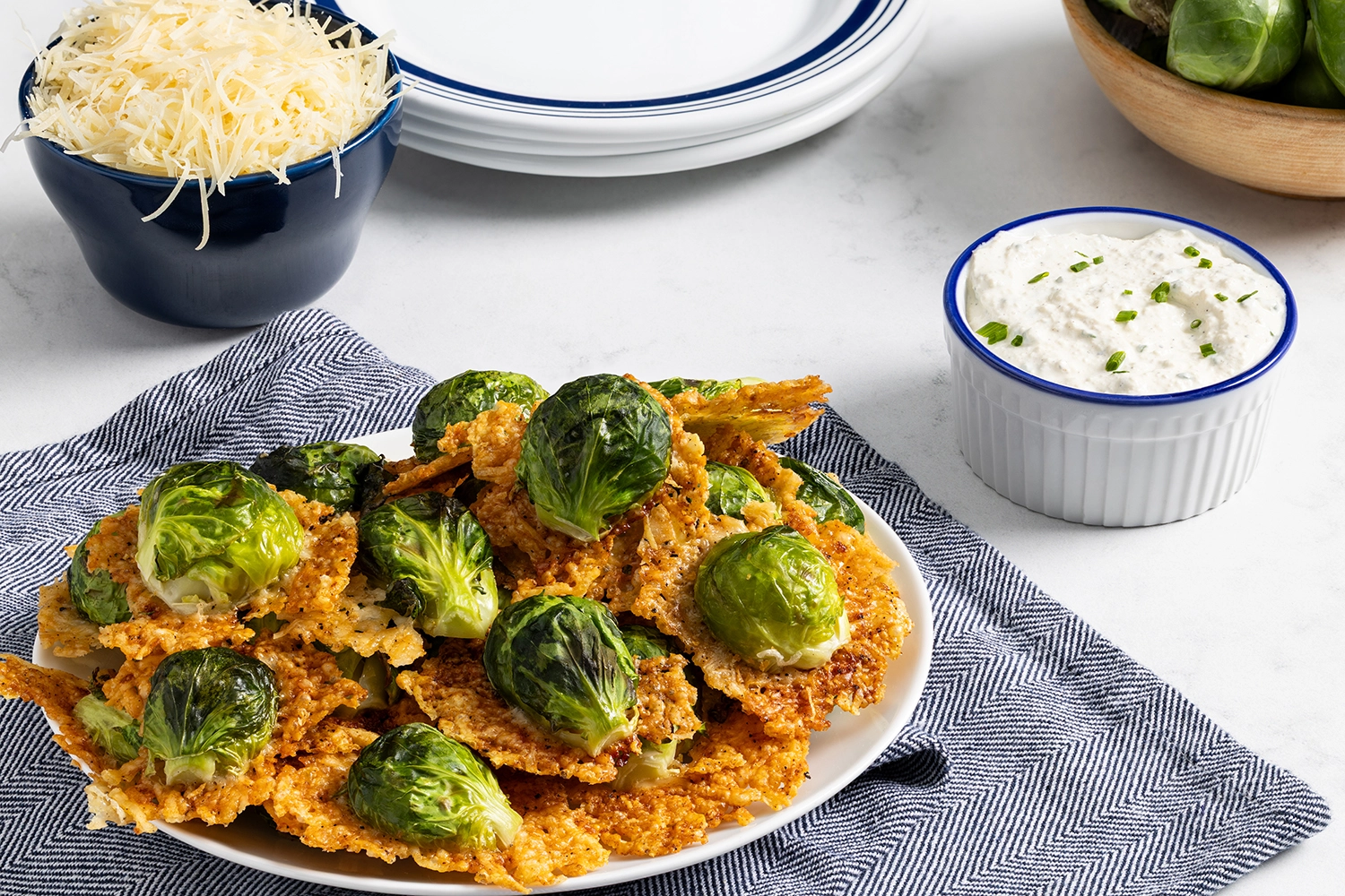 Parmesan brussels sprouts served on a plate accompanied by a Dijon chive cream sauce and shredded Parmesan.