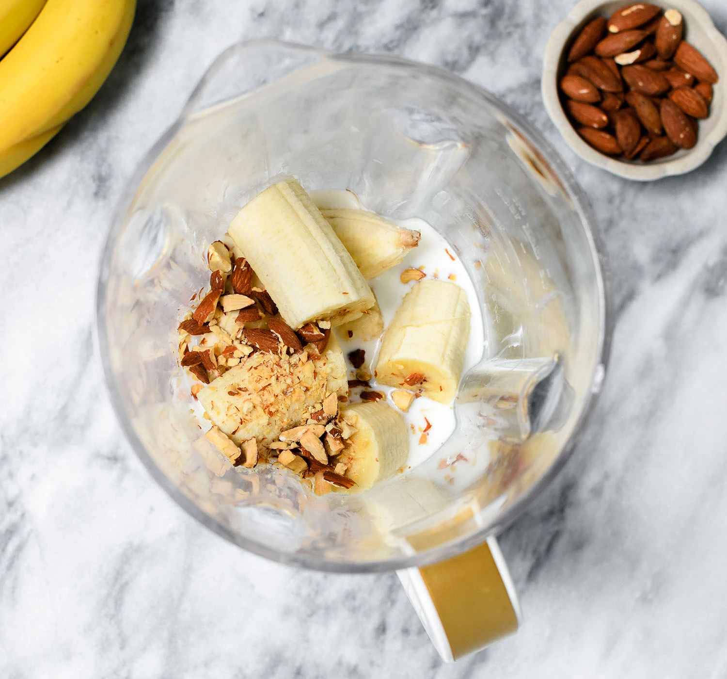 Ingredients for banana smoothie with vanilla yogurt and almonds in a blender.