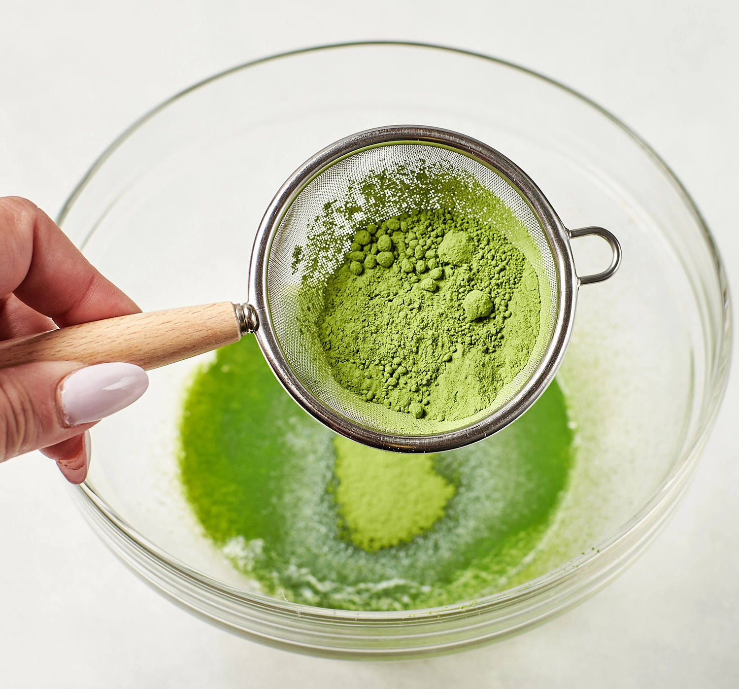 Sifting green tea matcha powder into a bowl.