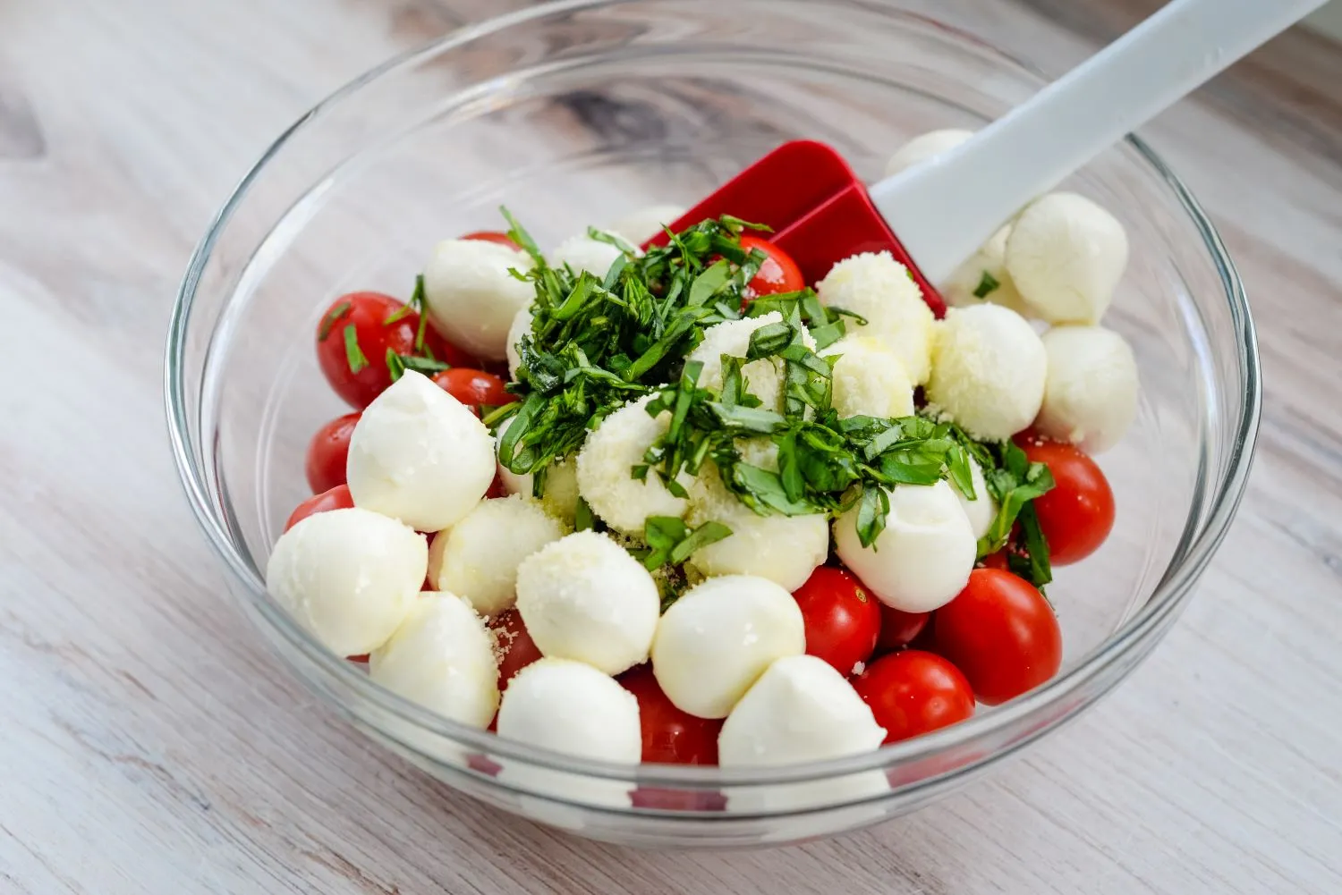 Mozzarella cheese, minced basil, and tomatoes mixed in a bowl to make a wreath salad