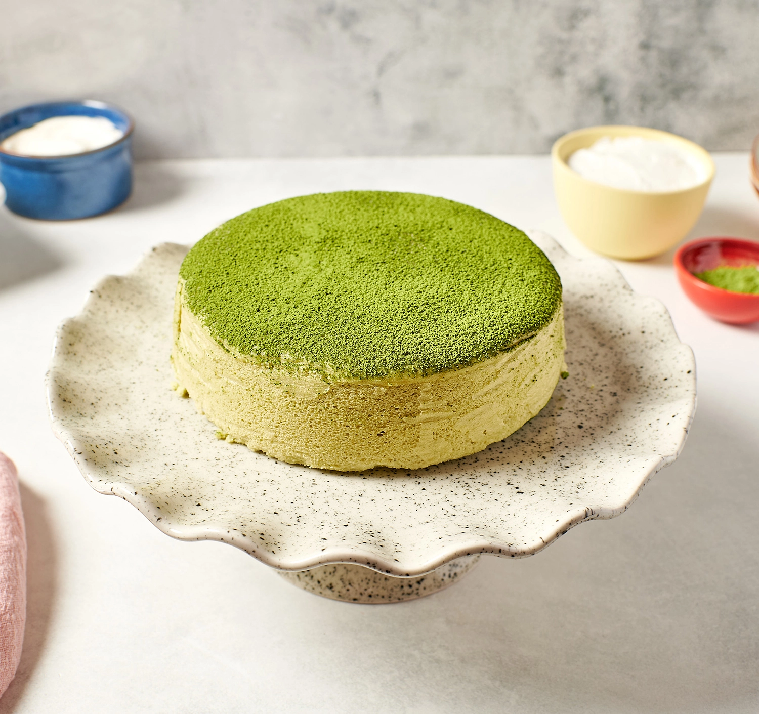 Whole Japanese matcha soufflé cheesecake dusted with green tea powder.