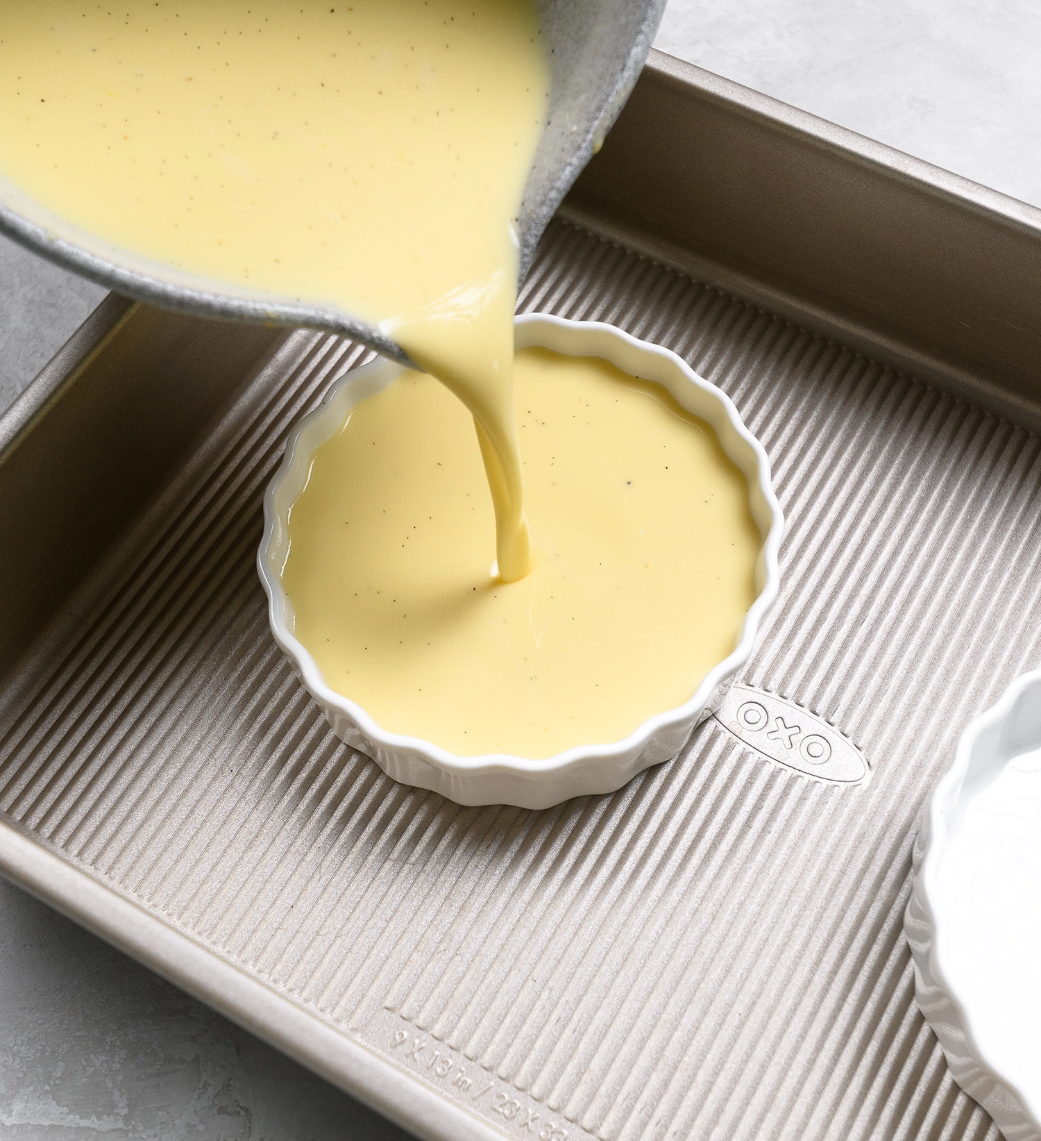 Strained creme brulee with Greek yogurt mixture poured into a ramekin.