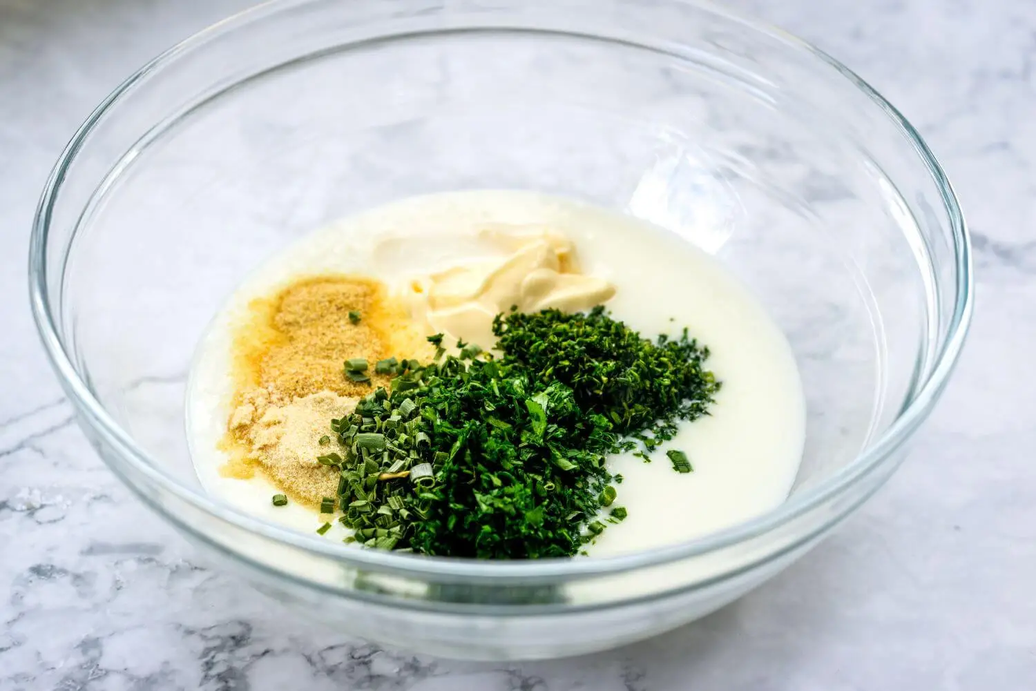 Ingredients that are used to make kefir ranch dressing in a bowl.