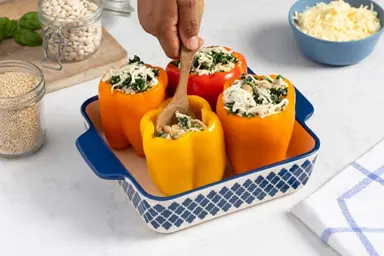 Bell peppers being stuffed with the spinach, quinoa, bean, and mozzarella cheese mixture to be baked.