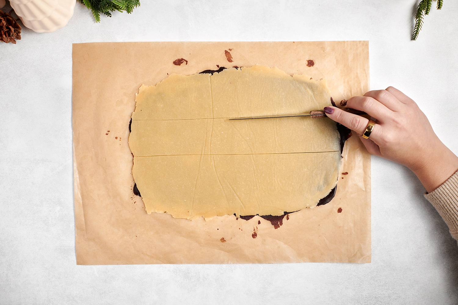 A hand draws a knife lengthwise across a rectangle of smooth and flat cookie dough
