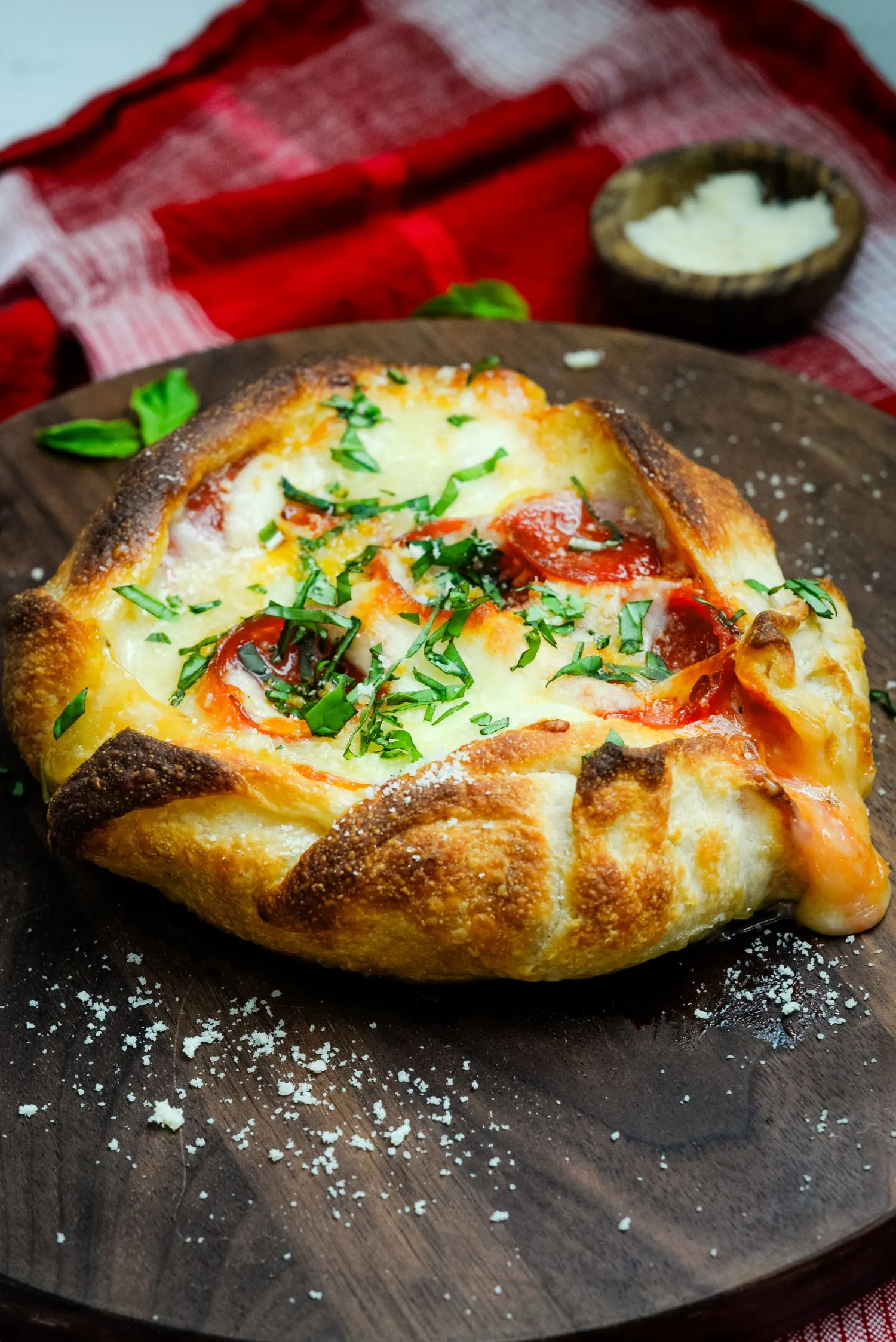 Fully baked stuffed Brie cheese pizza topped with fresh basil and Parmesan cheese