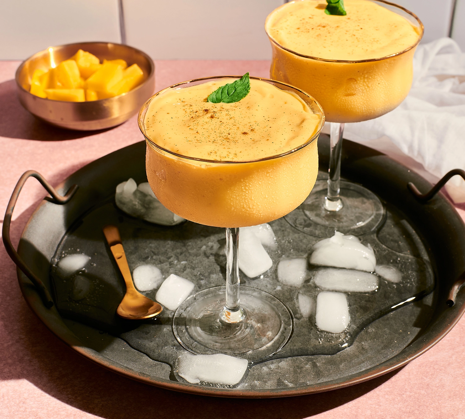 A glass of mango lassi with Greek yogurt topped with cardamom and ice ready to be served.