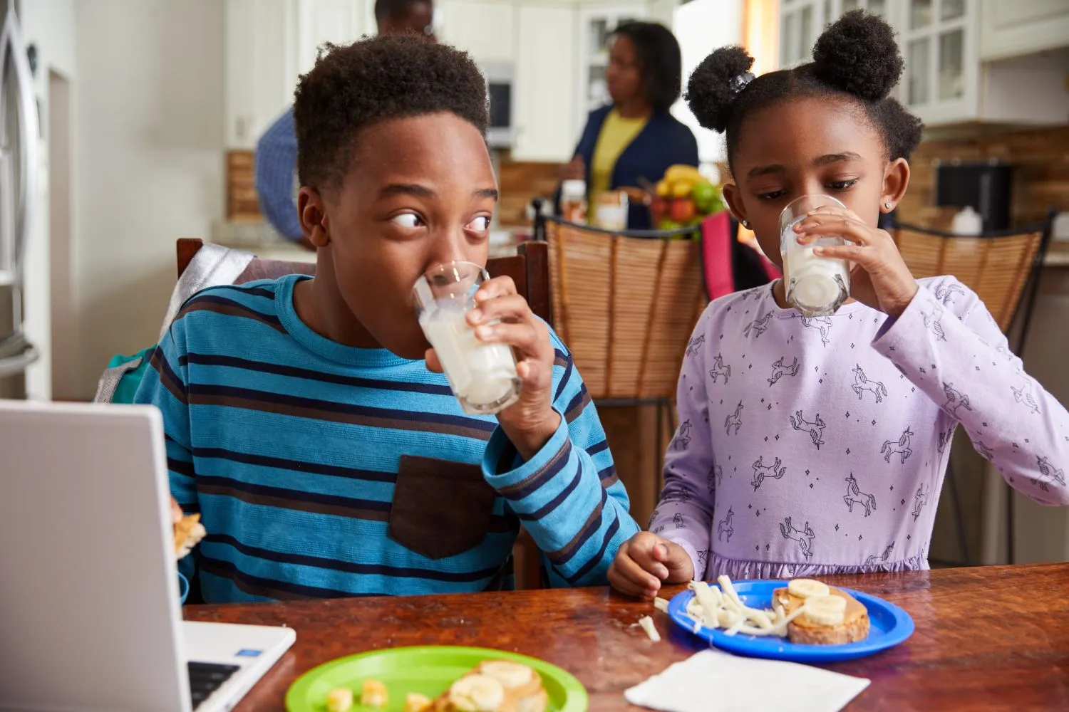 Two children drinking a glass of milk together.
