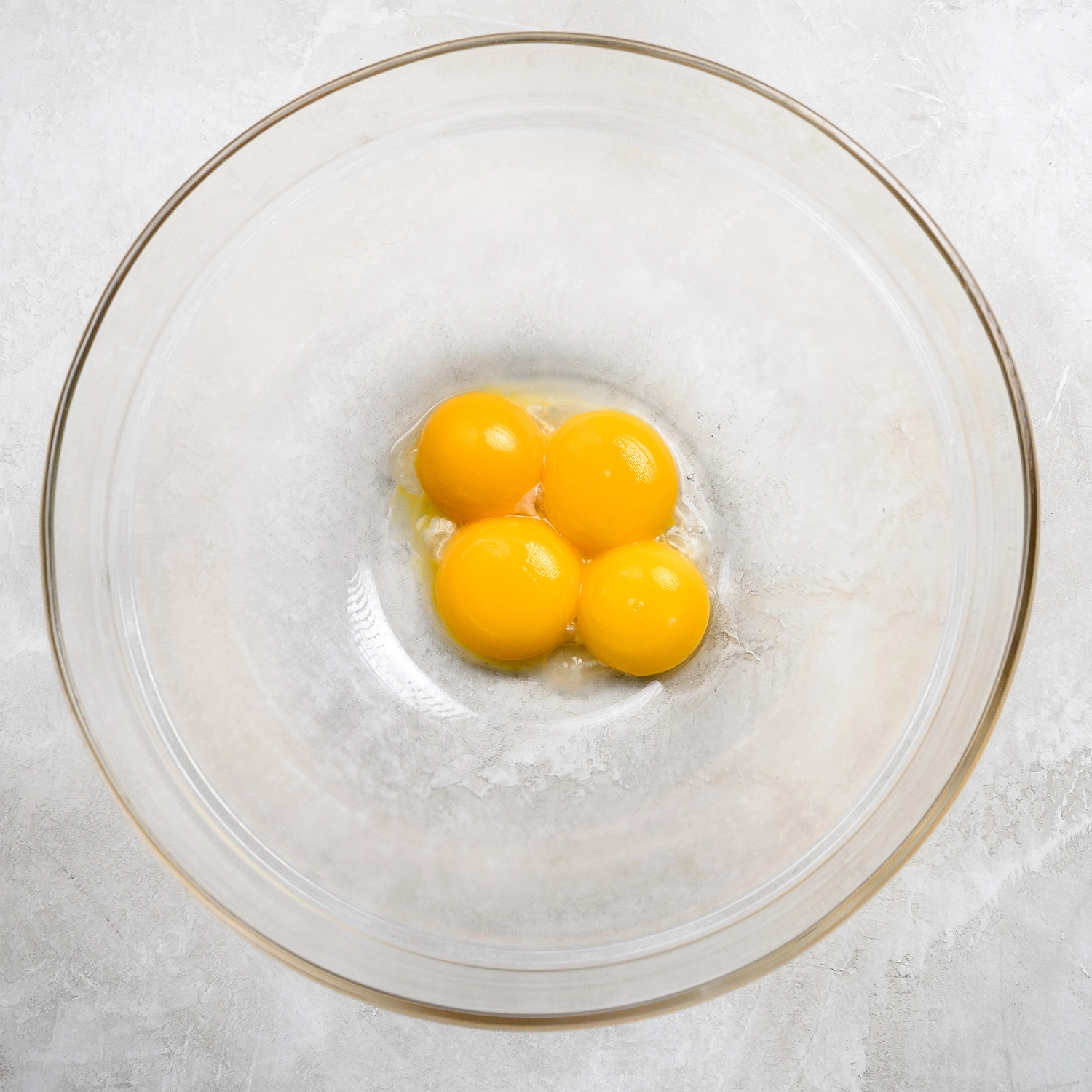 Four egg yolks separated in a bowl.