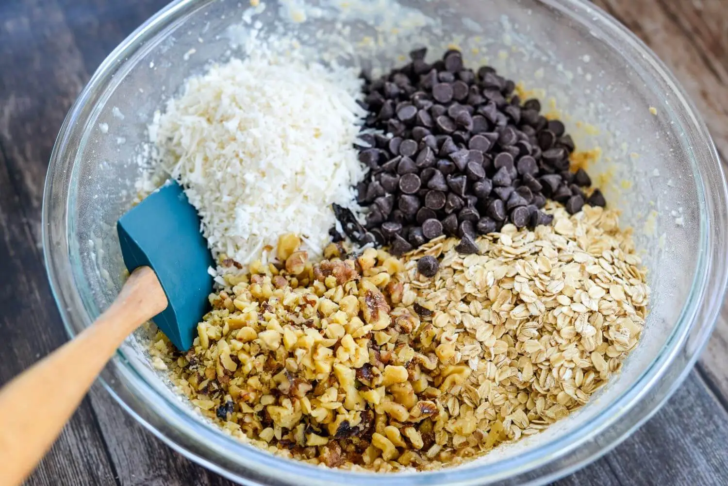 Nuts, oats, coconut, and chocolate chips together in a bowl.