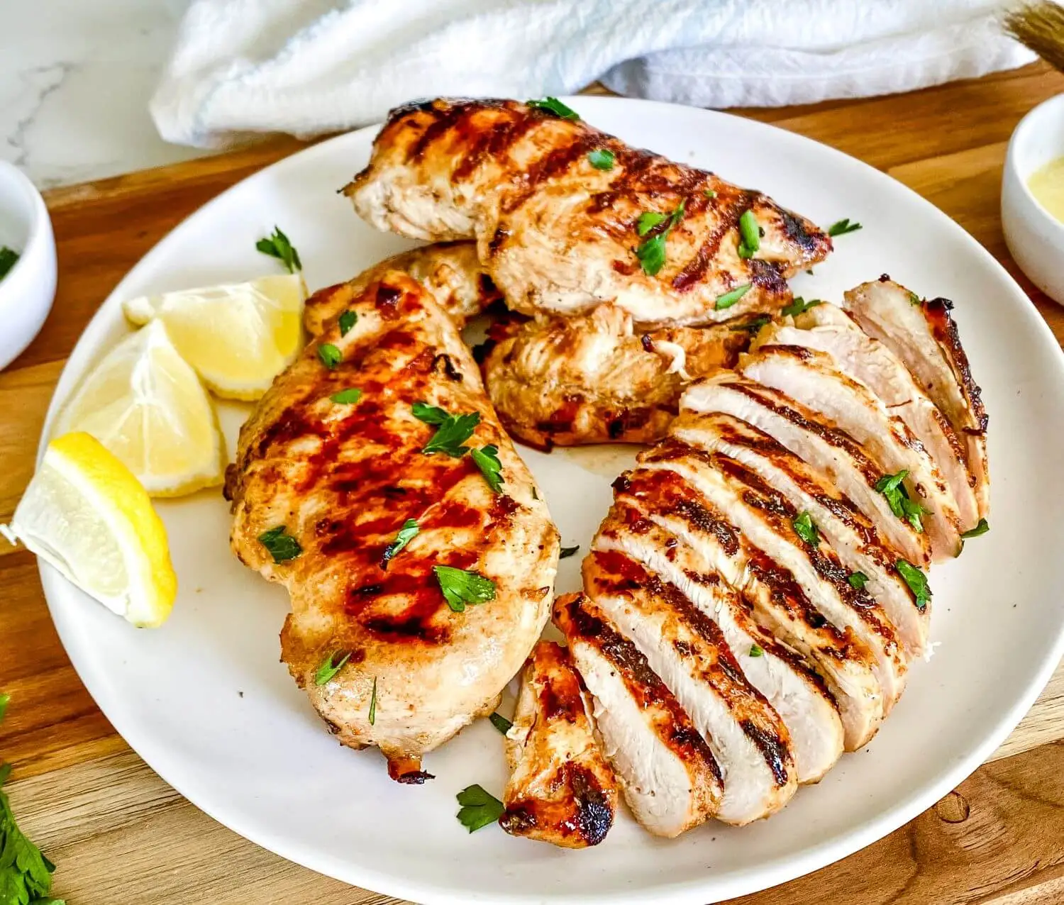Sliced kefir-brined barbecue chicken plated with lemons.