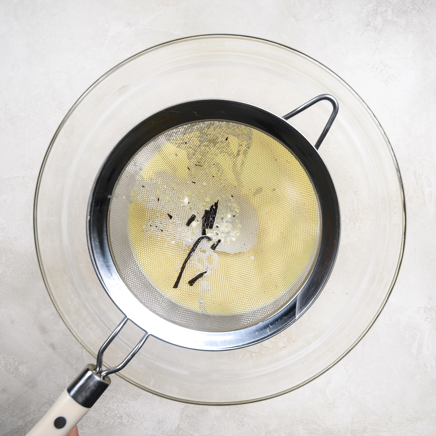 Eggs mixture strained through a sieve for a smooth custard.